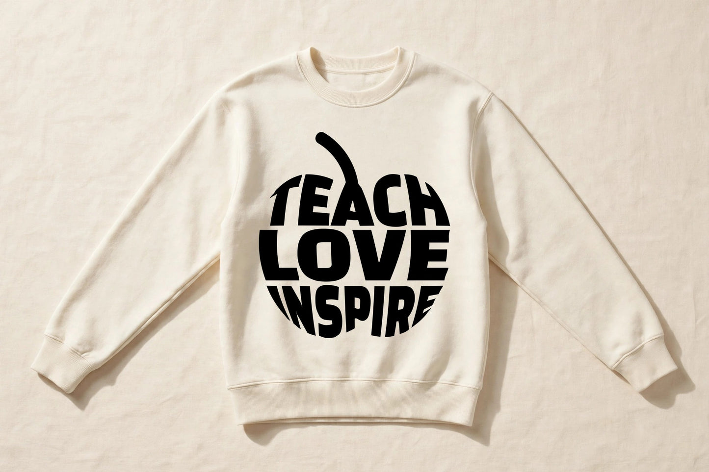 Teach Love Inspire cream crewneck sweatshirt laid flat with black apple word print