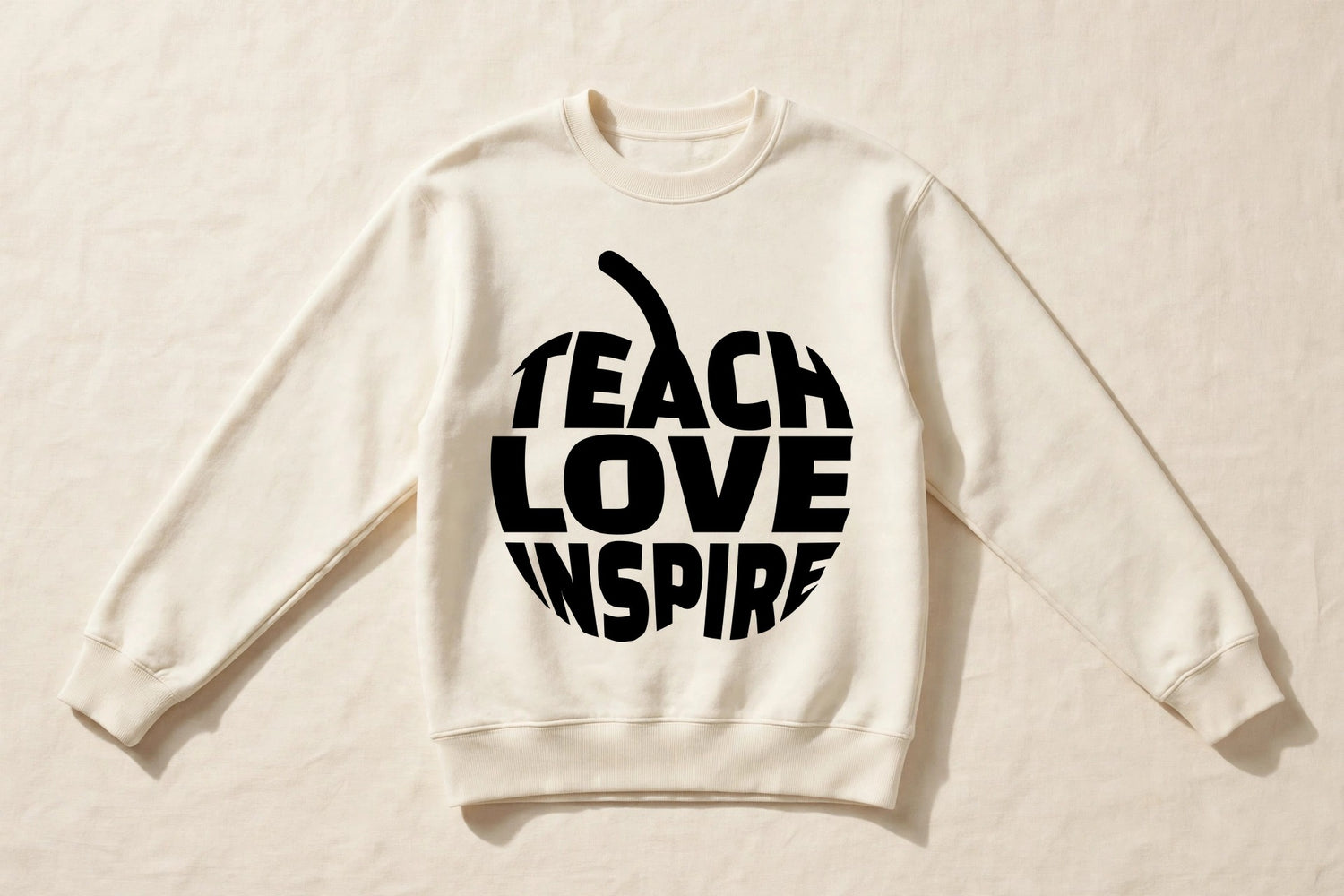 Teach Love Inspire cream crewneck sweatshirt laid flat with black apple word print