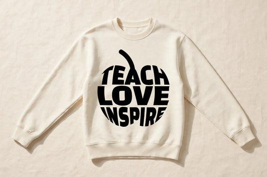 Teach Love Inspire cream crewneck sweatshirt laid flat with black apple word print